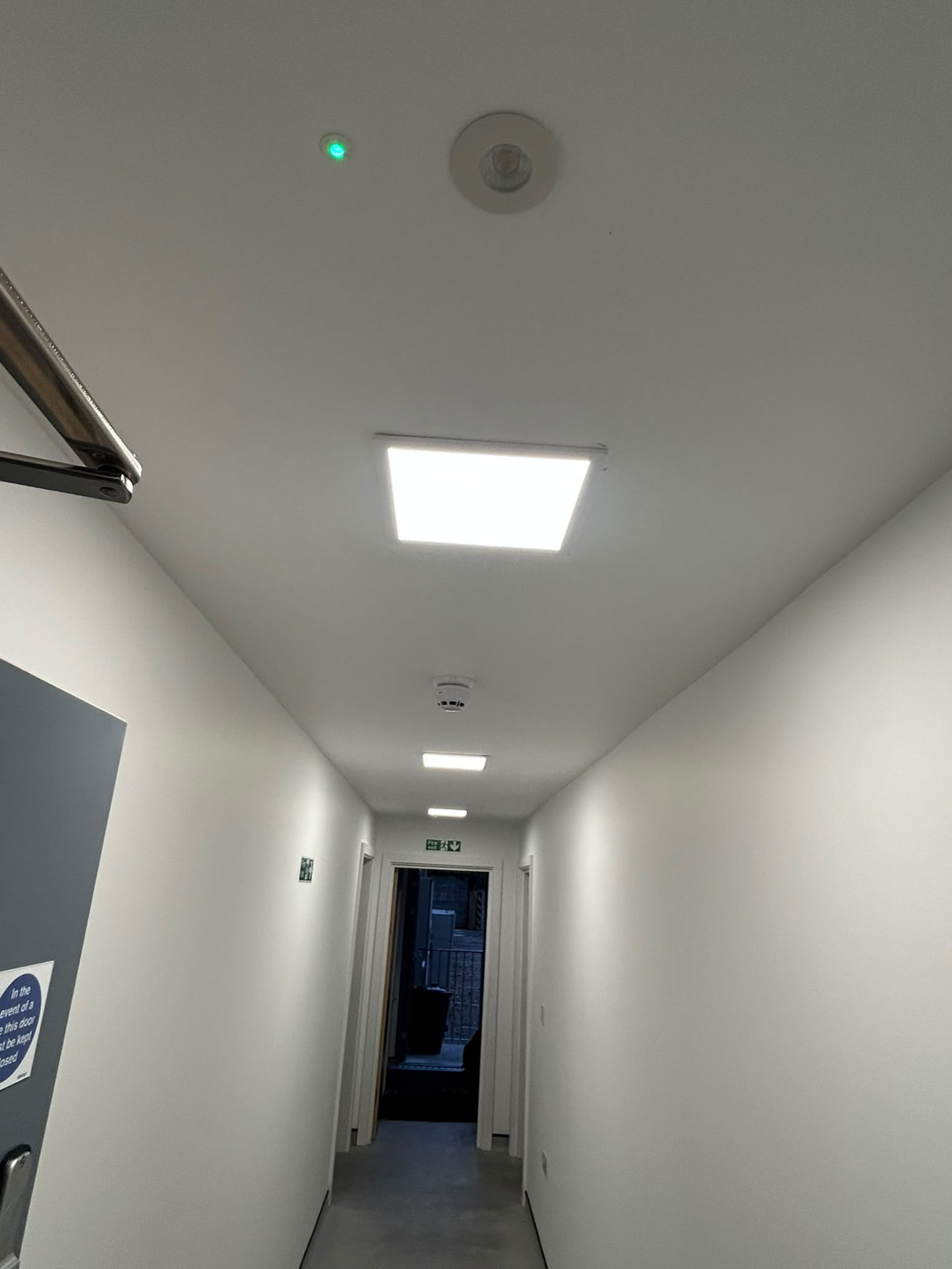 Commercial corridor with ceiling panel and emergency lighting